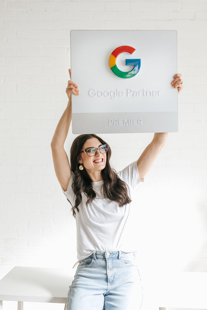 Kaity Griffin at her desk smiling and wearing a black tshirt that says Google Ads legend